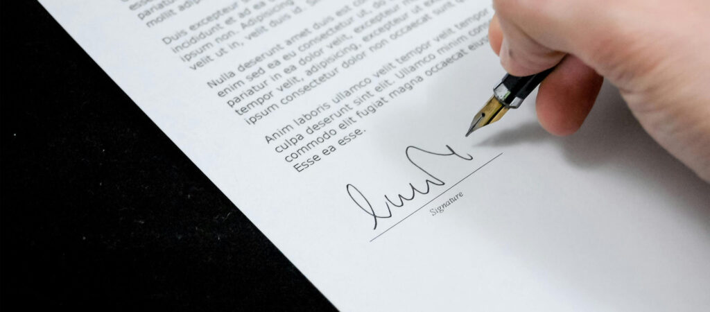 Persona firmando un contrato con pluma estilográfica