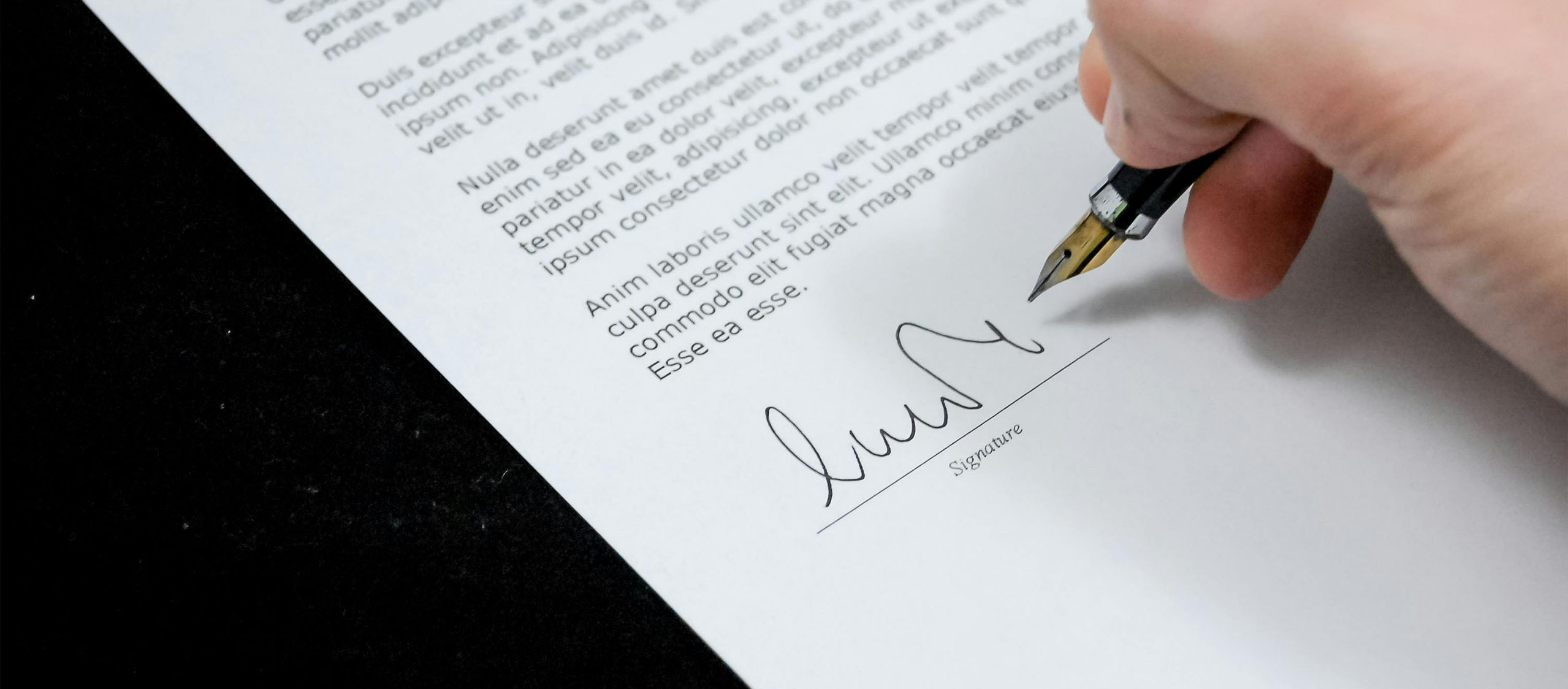 Persona firmando un contrato con pluma estilográfica